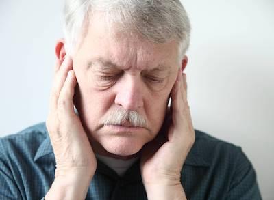 Man holding face in pain form TMJ and bruxism