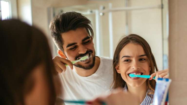 A couple brushing their teeth in the bathroom