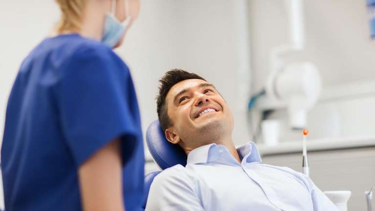 A smiling patient talking to his dentist