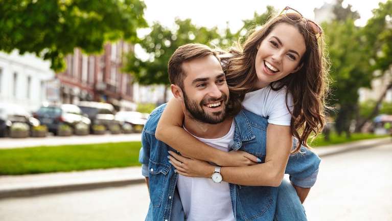 A couple smile warmly while embracing, symbolizing support and connection amidst stress-related oral