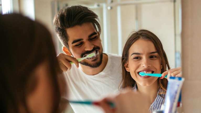 A father and daughter brushing their teeth
